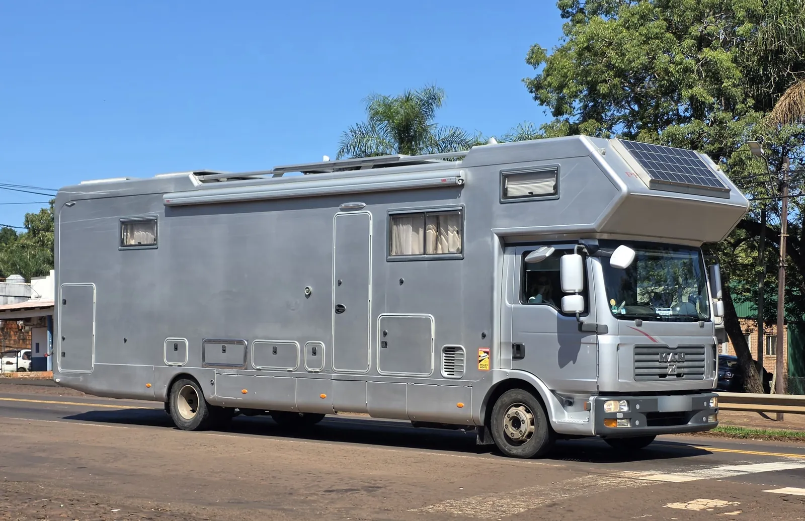 Autocaravana grande con una placa solar montada sobre la capuchina de la cabina y raíles en el techo