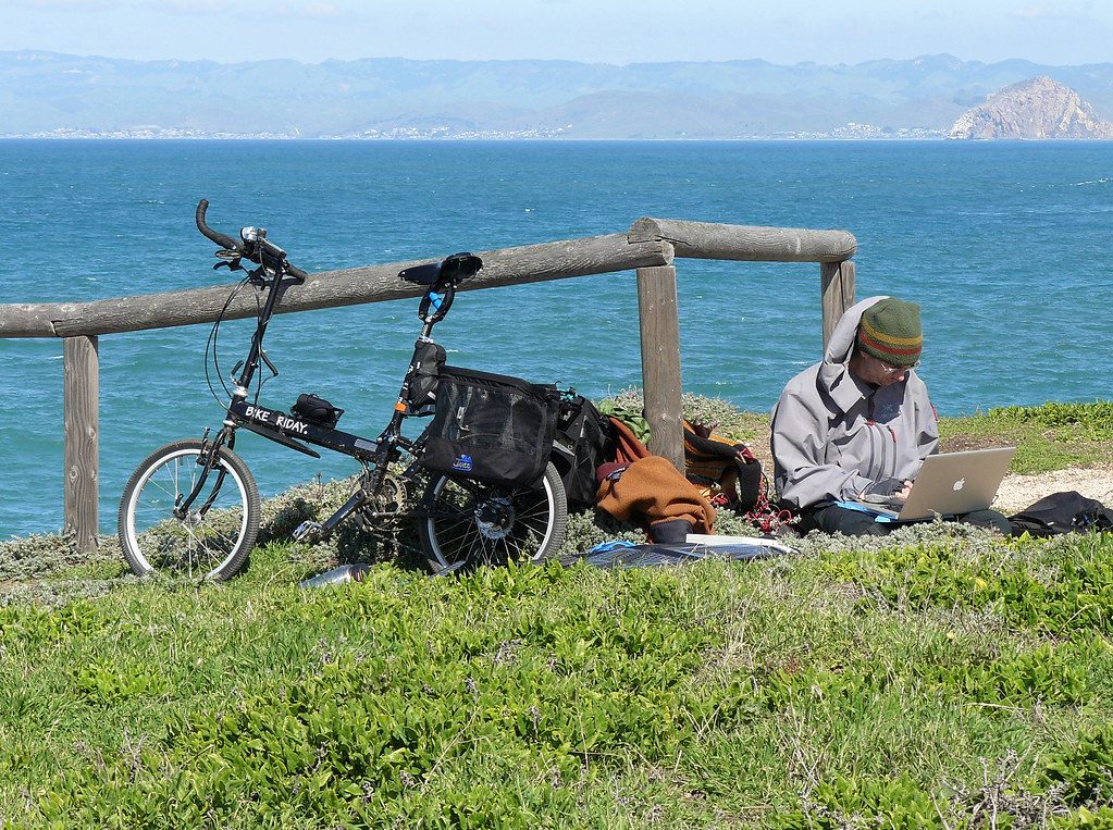 Viajero en bicicleta con un panel solar plegable portátil junto a la costa