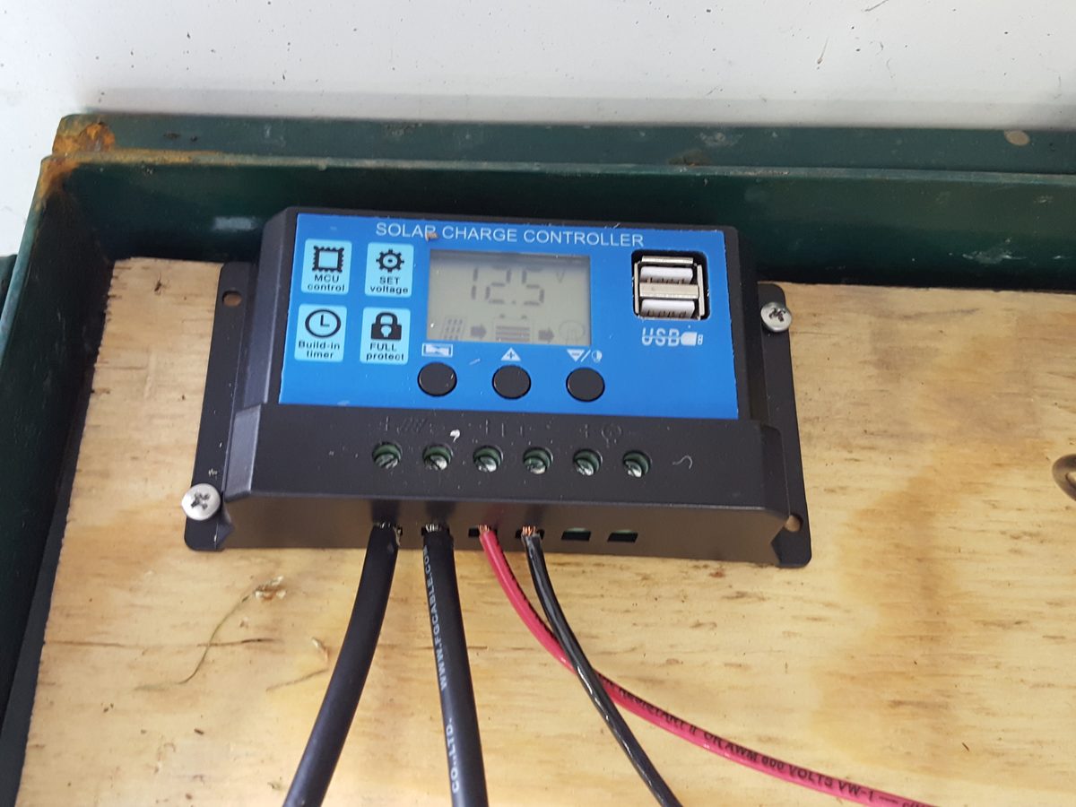 Regulador de carga solar con pantalla instalado sobre un tablero con los cables de panel y batería
