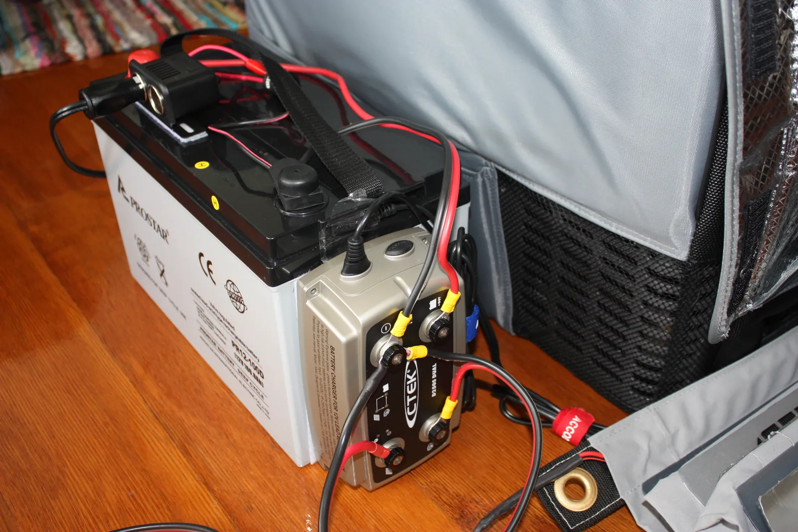 Batería auxiliar AGM con un cargador de batería a batería conectado junto a una nevera portátil de 12 V